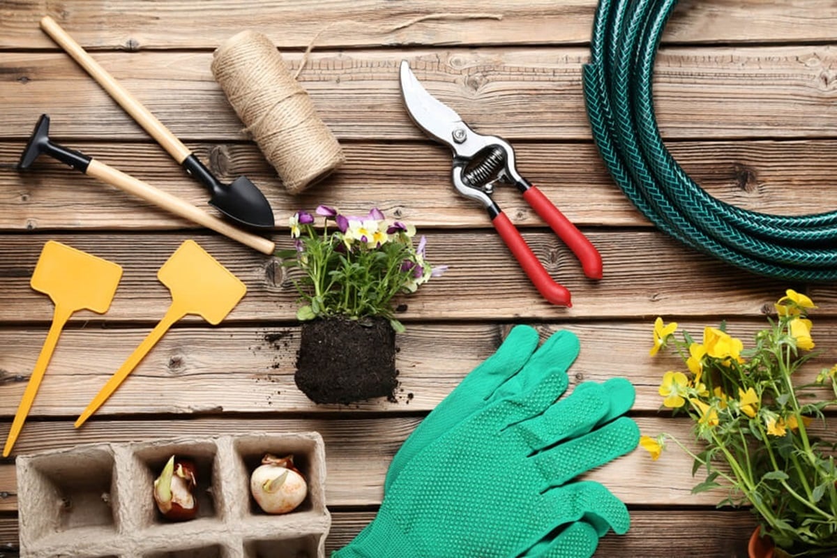 An assortment of garden tools and items laid out on a wooden table.