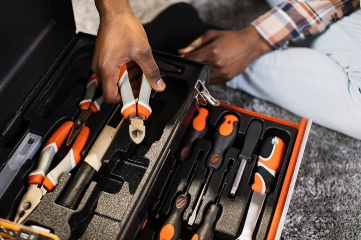 A person is reaching a tool from a set of tools in a toolbox.