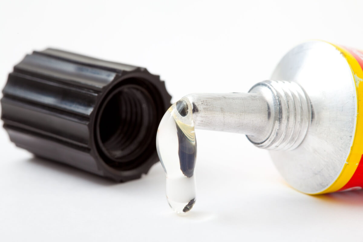 A tube of transparent adhesive, perfect for DIY projects, sits with its cap off, dispensing a small bead of glue.