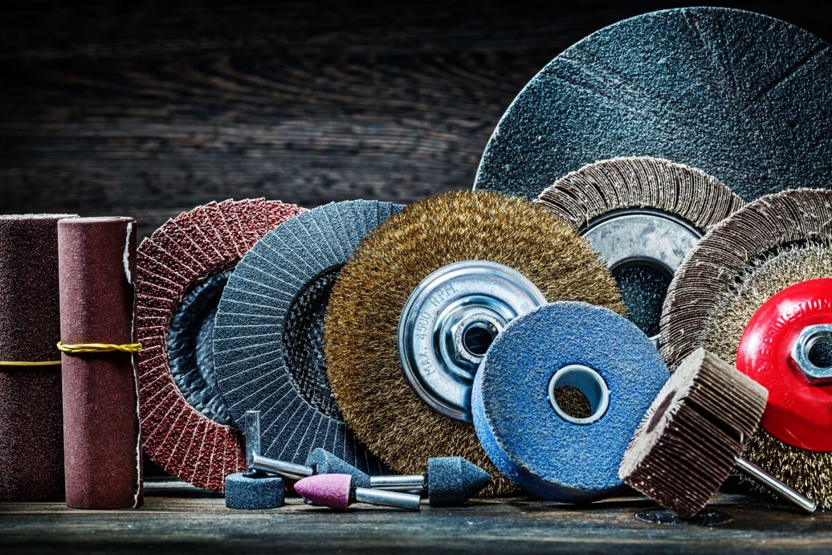 A selection of abrasive wheels and sanding tools, including backing pads, expertly arranged on a wooden surface.