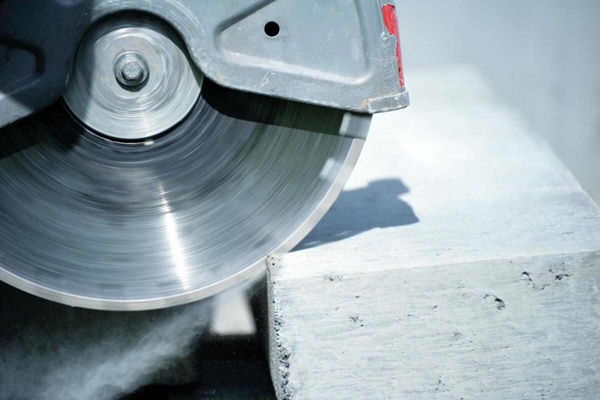 Close-up of a circular saw with diamond cutting grinding discs effortlessly slicing through a concrete block.